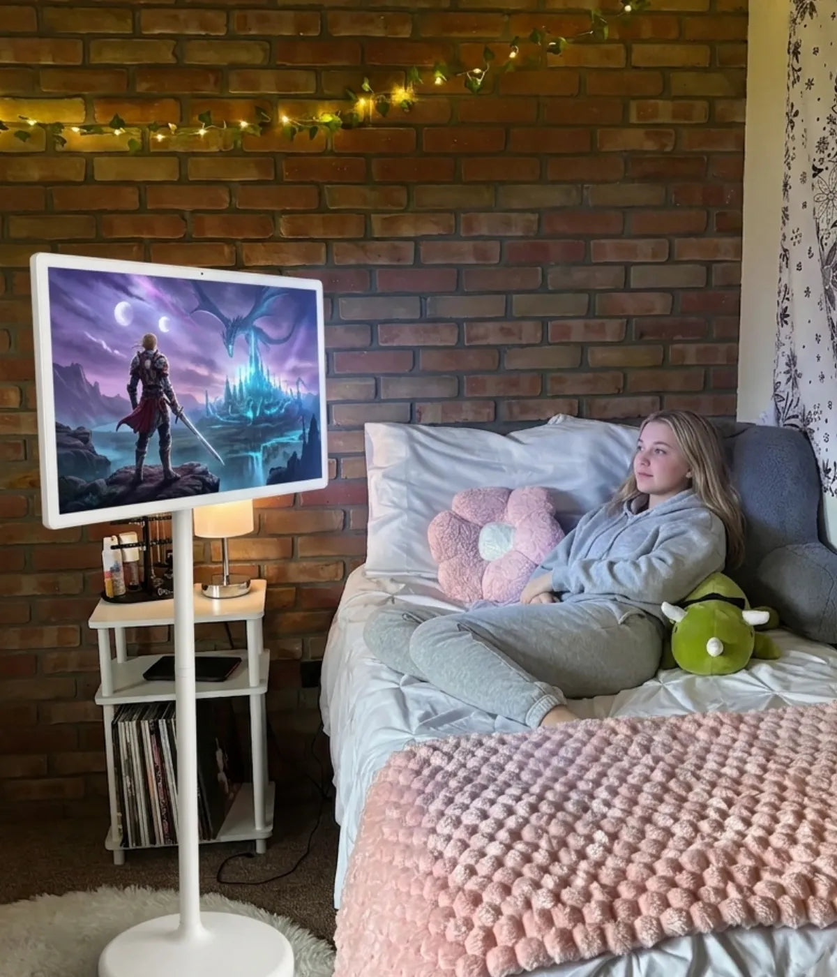 A girl is lying in bed, using a 32-inch 4K GFF portable screen on wheels to watch a movie